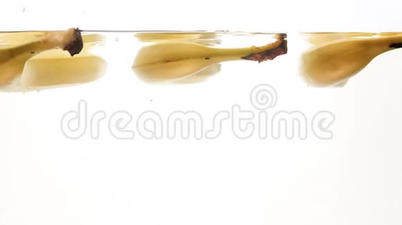 特写4k镜头三根成熟的香蕉在白色背景下漂浮在水中视频的预览图
