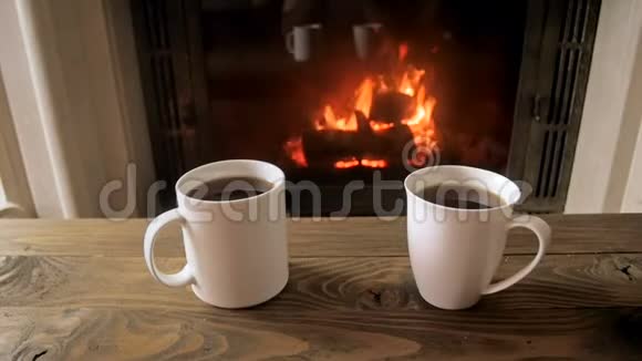 在燃烧的壁炉旁木桌上放两杯茶的特写慢动作视频视频的预览图
