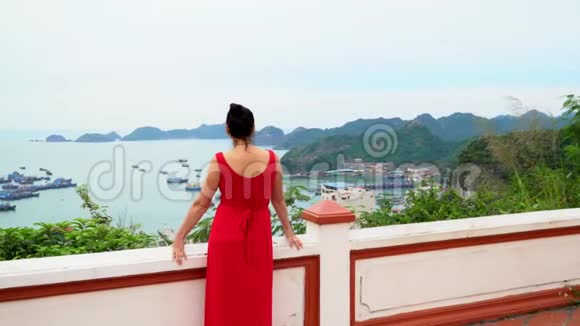 穿着红色裙子的女人花了一个时间回到镜头前看着越南的一个海湾海湾的美丽景色猫王视频的预览图