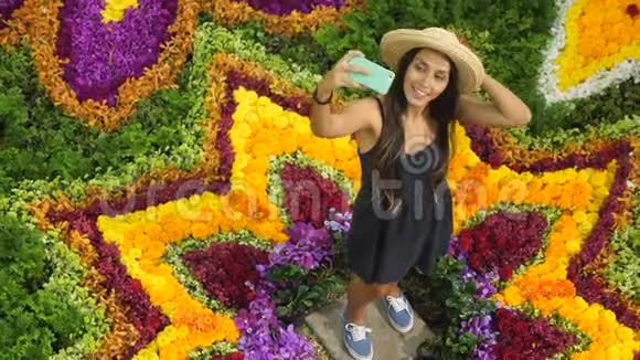 在温室美丽的花朵构图中年轻的混合种族妇女制作手机自拍4K视频的预览图