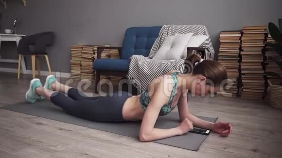 健身妇女使用智能手机在家做木板运动视频的预览图