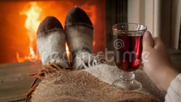 慢镜头拍摄的女人穿着温暖的羊毛袜在壁炉边喝茶视频的预览图