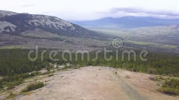 地平线上有山景的山谷的顶部景观剪辑以森林地区徒步旅行者为背景的小径视频的预览图