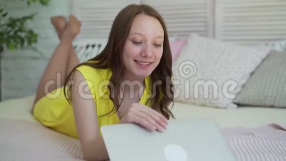 家里的女孩躺在床上拿着笔记本电脑视频的预览图
