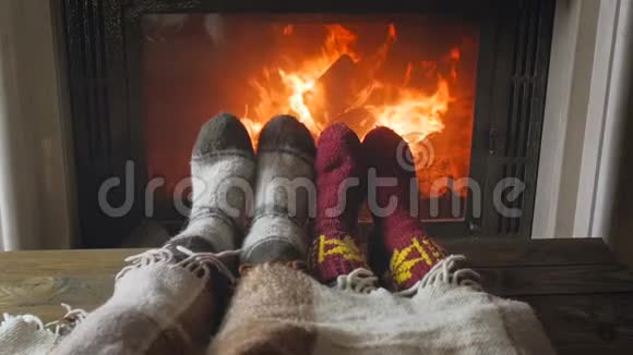 一对穿着针织毛袜的情侣在燃烧的壁炉边放松的慢动作视频视频的预览图