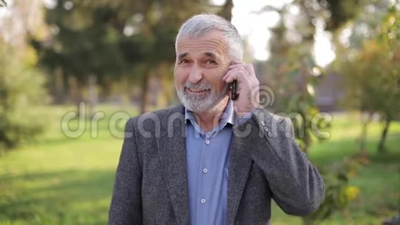 快乐的老人在电话旁和别人说话英俊的老人长着美丽的胡须微笑着快乐着视频的预览图