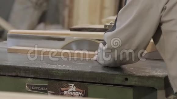 掌握在机器上用木头工作一个穿灰色夹克的男人一辆车和一个纺车一个接一个地锯着木梁视频的预览图