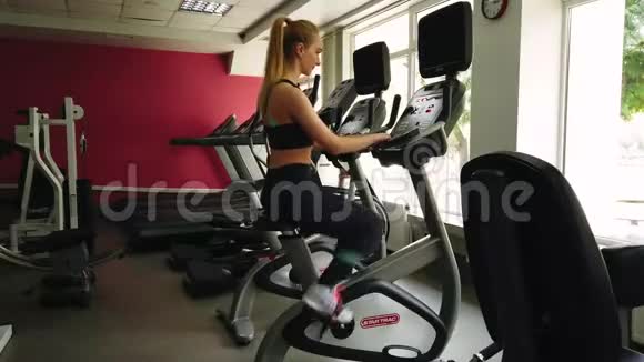 年轻女孩在运动健身房骑着运动自行车跑步视频的预览图