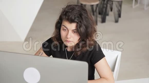 卷毛和穿孔的女人正在电脑上认真工作视频的预览图