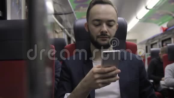 年轻商人在火车上看智能手机的肖像视频的预览图