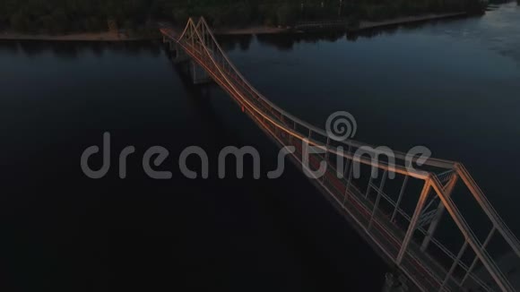 日落时分行人天桥在城市附近的河流上空盘旋视频的预览图