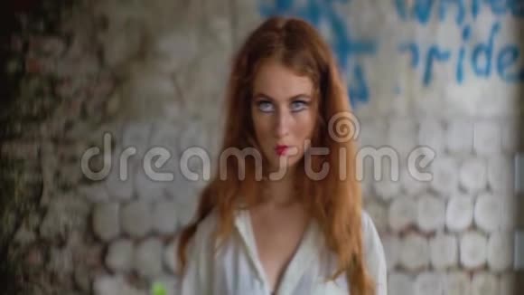 有金属病的女人的肖像红色的口红和头发看着肮脏的破墙上的相机视频的预览图