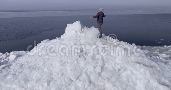 鸟瞰年轻活跃的快乐男子停留在冰冰冰川附近的冬季海洋海岸线无人机视图视频的预览图