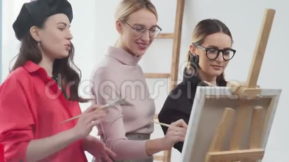 女艺术家站在画架上一起画一幅画视频的预览图
