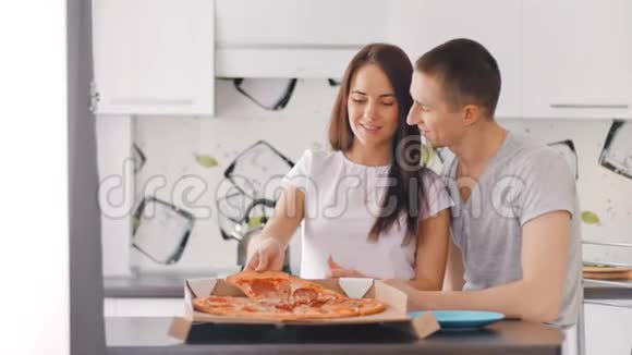 年轻的幸福夫妇打开盒子把披萨放进盘子里视频的预览图
