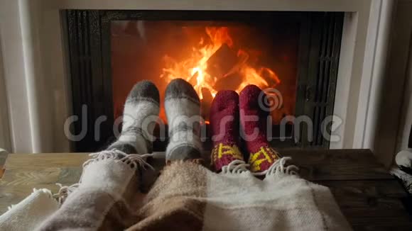 一对徜徉的情侣躺在毯子下晚上用燃烧的壁炉温暖双脚视频的预览图