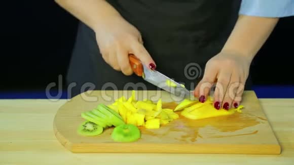 雌性的手在木板上切割猕猴桃和芒果视频的预览图
