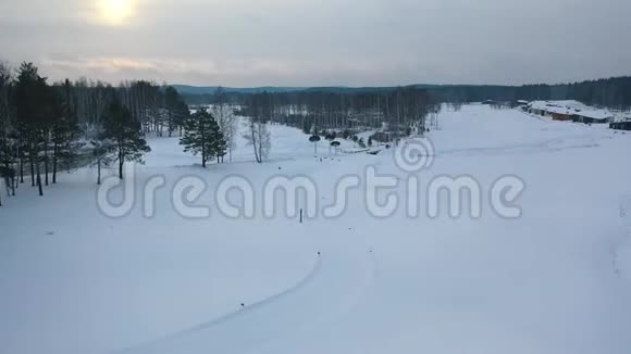冬季在灰色的夜空下滑雪道和滑雪屋在森林附近的空中观景录像体育运动视频的预览图