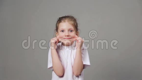 可爱的小女孩扮演猿猴滑稽的女孩在灰色背景上露出鬼脸视频的预览图