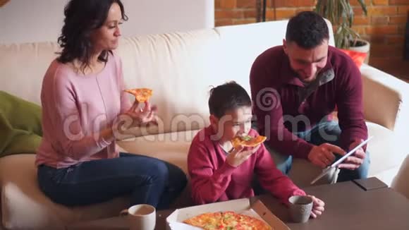 家庭在客厅吃披萨时使用数码平板电脑视频的预览图