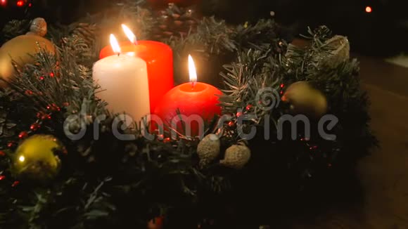 在圣诞花环上摄像机沿着三支燃烧的蜡烛缓缓移动视频的预览图