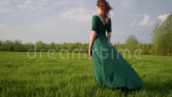 年轻漂亮的女人穿着漂亮的裙子站在夕阳下的田野里视频的预览图