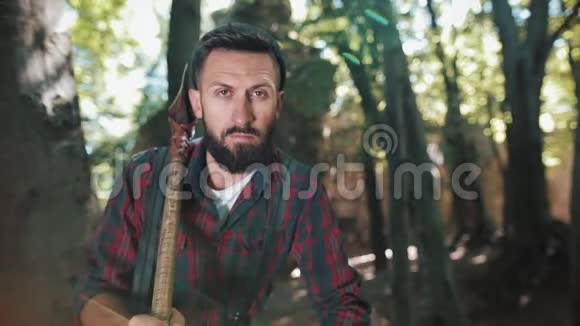 严肃自信的伐木工人的肖像成年胡须男拿着一把大斧头在户外看着镜头视频的预览图