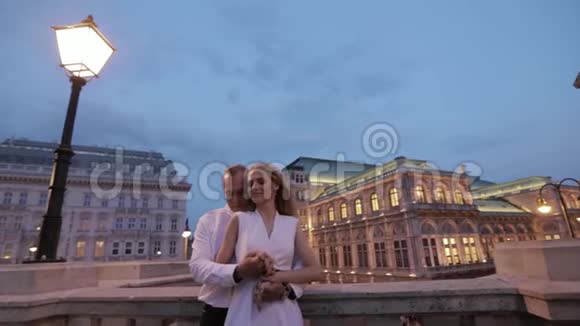 幸福的一对夫妇晚上在城里散步维也纳奥地利歌剧院附近的看台视频的预览图