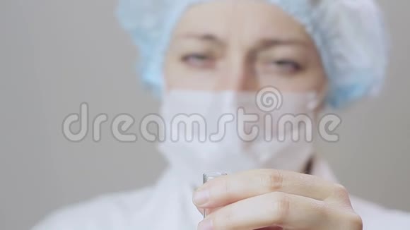 一名身穿白衣的女医生和防护手套将蓝色液体倒入试管中视频的预览图