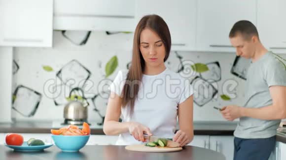 幸福的一对夫妇一起在清淡的厨房做饭年轻女子切碎蔬菜准备健康午餐视频的预览图