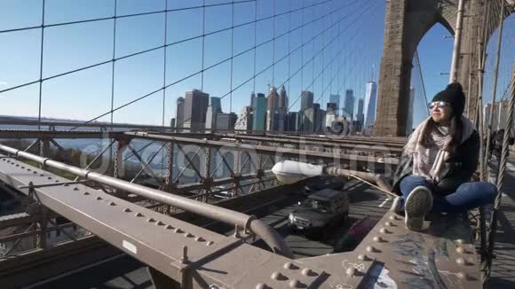 年轻的美女在布鲁克林大桥上放松同时欣赏令人惊叹的景色视频的预览图