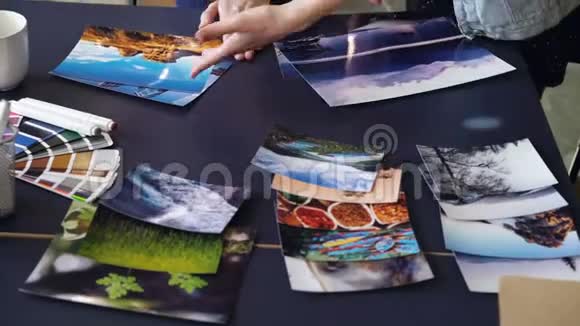 在现代办公室里女人双手把照片放在桌子上的倾斜镜头女设计师按颜色对图片进行分组视频的预览图