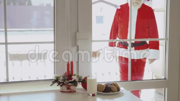 圣诞老人透过桌子上的窗户看着牛奶和饼干视频的预览图