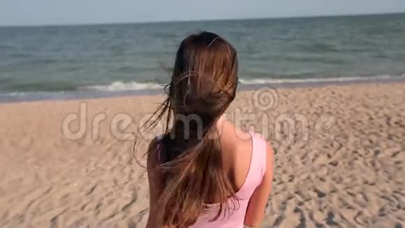 在海滩上漫步到海水中的女人的后景转身邀请她去度假旅行苗条的女士视频的预览图