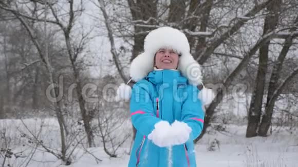 快乐的女人在森林里用手扔雪雪落在阳光下闪闪发光女孩在冬天玩耍视频的预览图