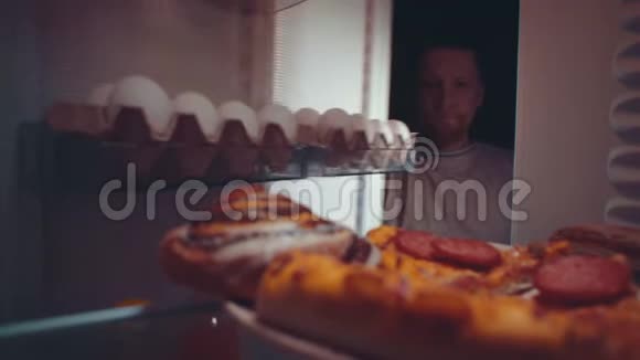 一个年轻人晚上从冰箱里拿食物视频的预览图