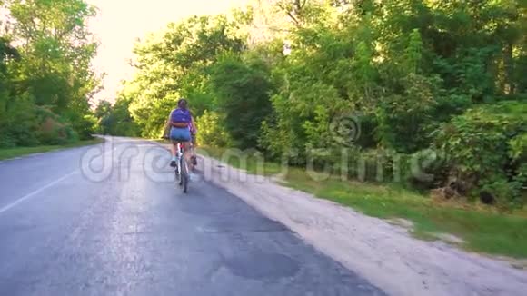 一对年轻夫妇在一个晴朗的日子骑自行车在森林道路上视频的预览图