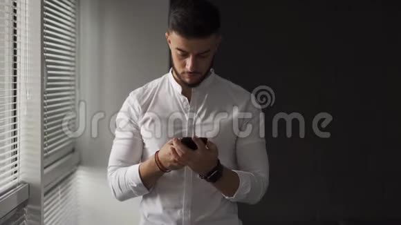 英俊的年轻人在智能手机上聊天和发短信在智能手机上滚动视频的预览图
