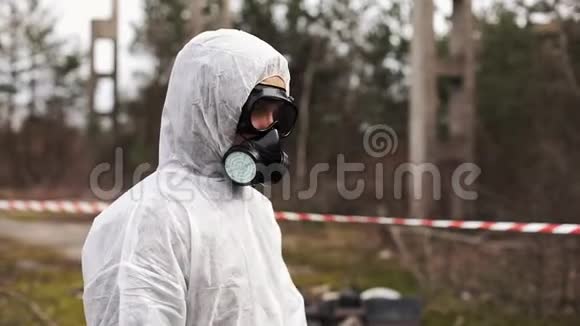 穿着生物危险服和防毒面具的人走到满是废物的土地上的高跷前视频的预览图