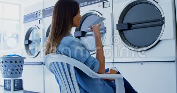 女士在自助洗衣店4k打手机视频的预览图