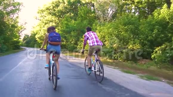 一对年轻夫妇在一个晴朗的日子骑自行车在森林道路上视频的预览图