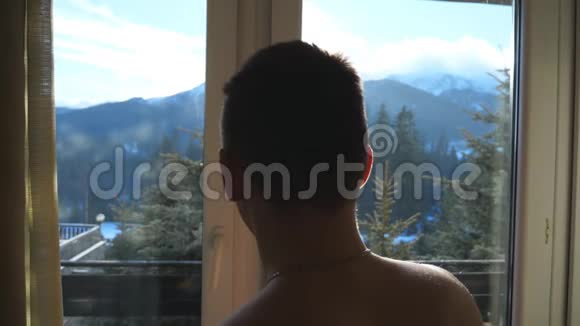 年轻的运动员在酒店的卧室打开窗户在冬天的时候在阳台上散步帅哥视频的预览图