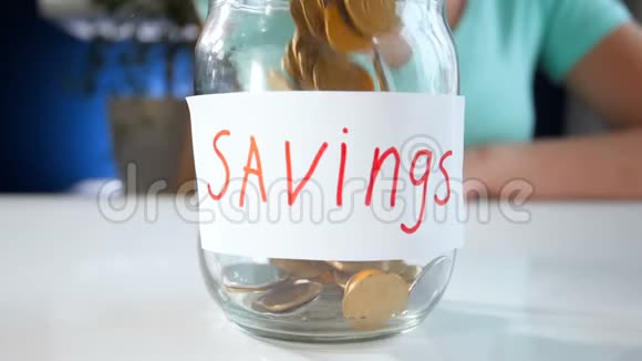 小女人用玻璃罐装满钱储蓄的画面视频的预览图