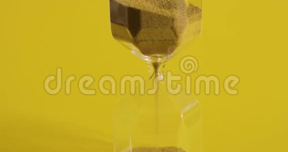 黄色背景上的玻璃沙子正从一个部分倾泻到另一个部分时间和瞬变概念视频的预览图