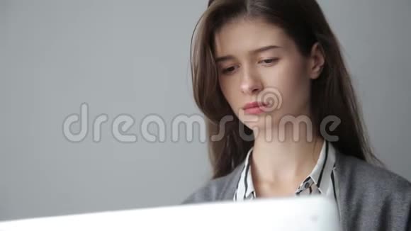 年轻女商人通过电脑工作灰色背景视频的预览图