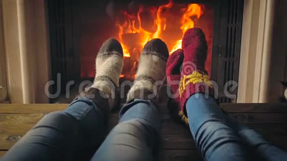 两个穿羊毛针织袜子的人在壁炉取暖的画面视频的预览图