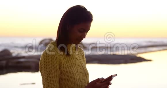 美丽的女人在海边用手机视频的预览图