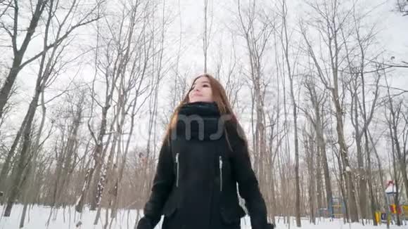 一个快乐的女孩在冬天的公园里快乐地跳舞视频的预览图