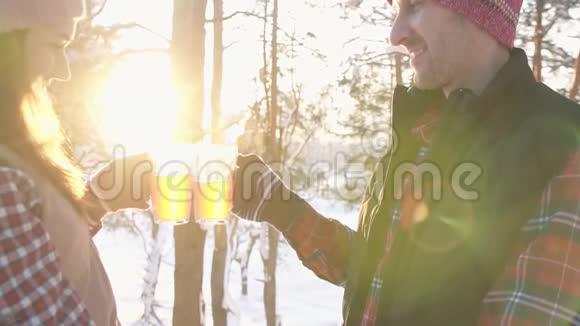 一对穿着冬衣的年轻人在冬林日落时喝着热覆盖的酒寒假视频的预览图