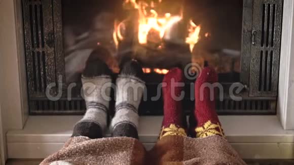 一对情侣穿着针织暖袜躺在燃烧的壁炉旁的慢镜头视频的预览图